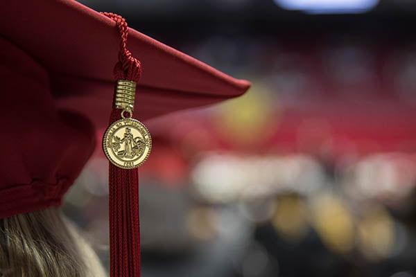 A golden ua seal hangs from a student's mortarboard